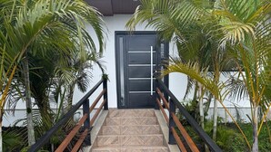 Un escalier orné de carreaux décoratifs, doté de rampes en métal noir et bordé de palmiers.