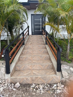 Un escalier orné de carreaux décoratifs, doté de rampes en métal noir et bordé de palmiers.