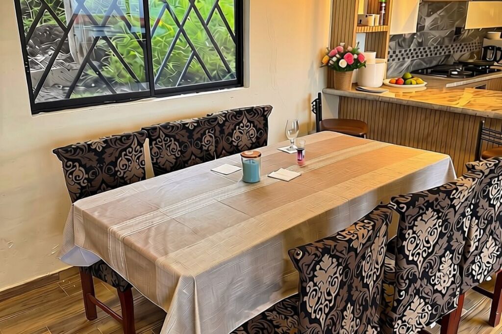Zona pranzo con tavolo apparecchiato per due, una panca e vista su un angolo cottura.