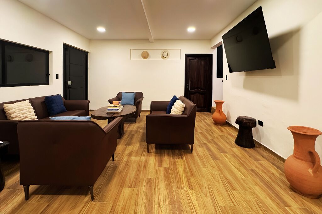 A living room with a sofa, armchairs, a coffee table, and a flat-screen TV mounted on the wall.