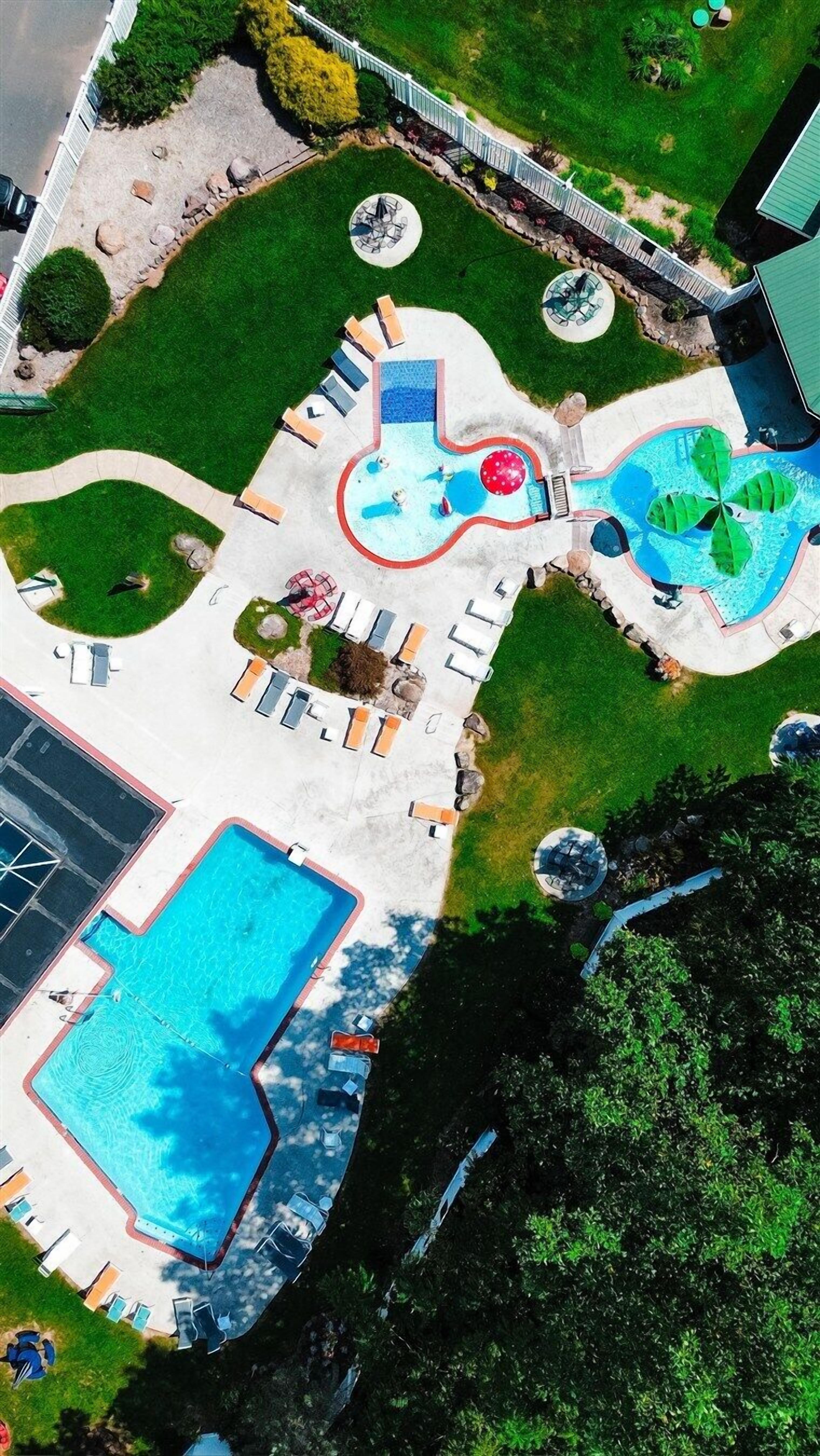 An aerial view of a resort with a swimming pool, lounge areas, and a bridge connecting different sections.