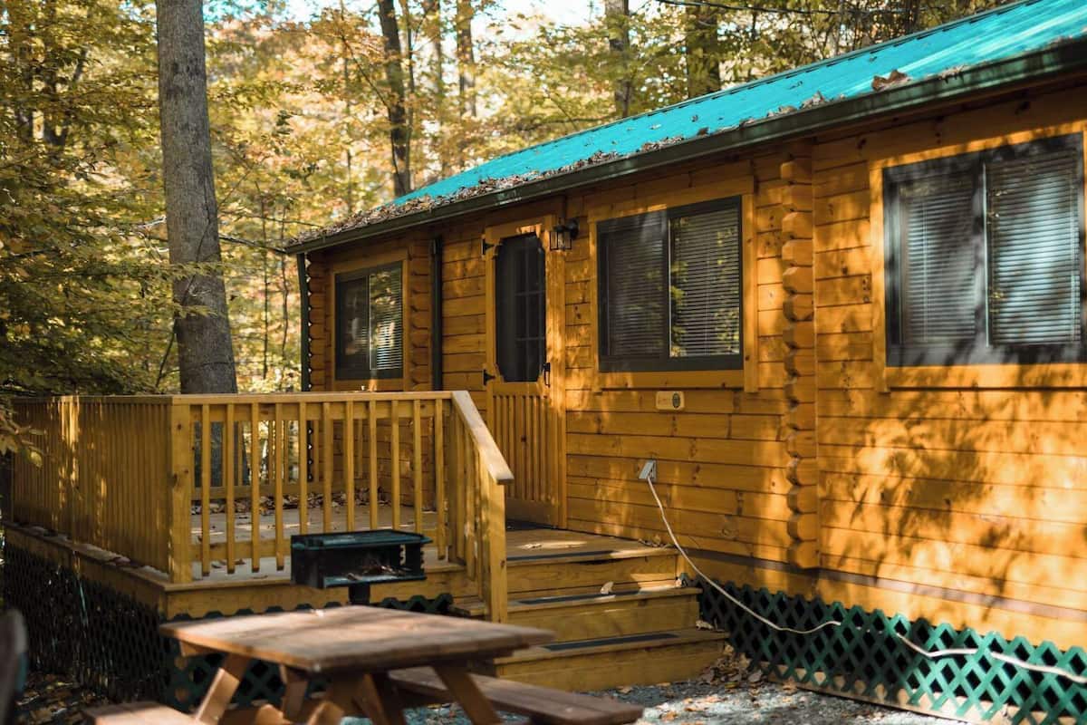 A cabin with a wooden deck, a fireplace, and a covered outdoor area.