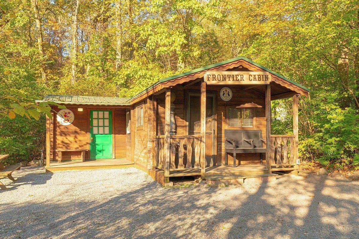 A wooden cabin labeled 'FRONTIER CABIN' with a porch and a green door.
