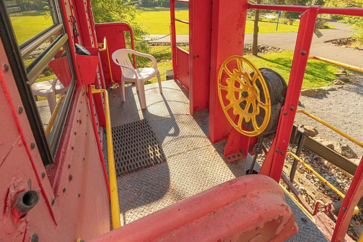 Una estructura mecánica roja y amarilla con una silla de plástico blanca y una rejilla metálica.
