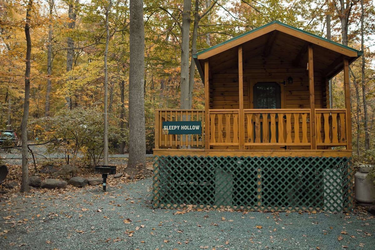 A small wooden cabin labeled 'SLEEPY HOLLOW' with a balcony, surrounded by trees.