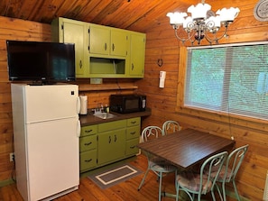 Una cocina compacta con refrigerador, microondas y gabinetes verdes.