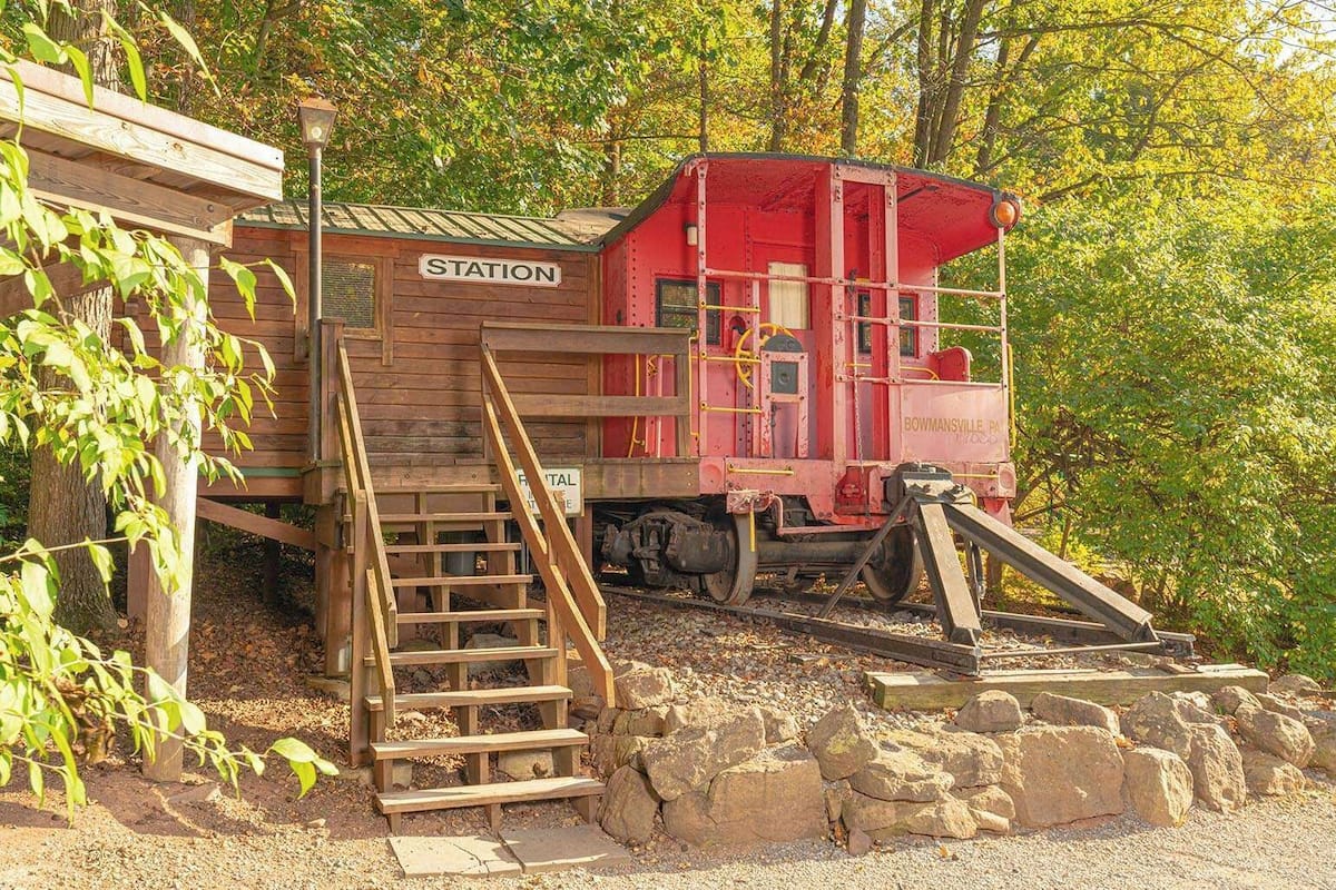 A vintage red train car labeled 'BOWMANSVILLE PA' with a wooden staircase leading up to a platform.