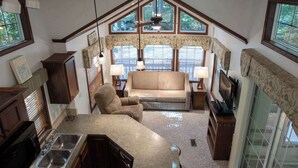 A cozy living room with a sofa, armchair, and a dining area with a sink and cabinets.