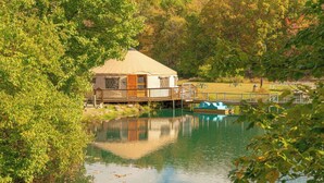 A lakeside cabin with a deck, a dock, and a small boat.