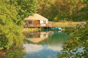 Una cabaña junto al lago con un muelle, un embarcadero y un bote pequeño.