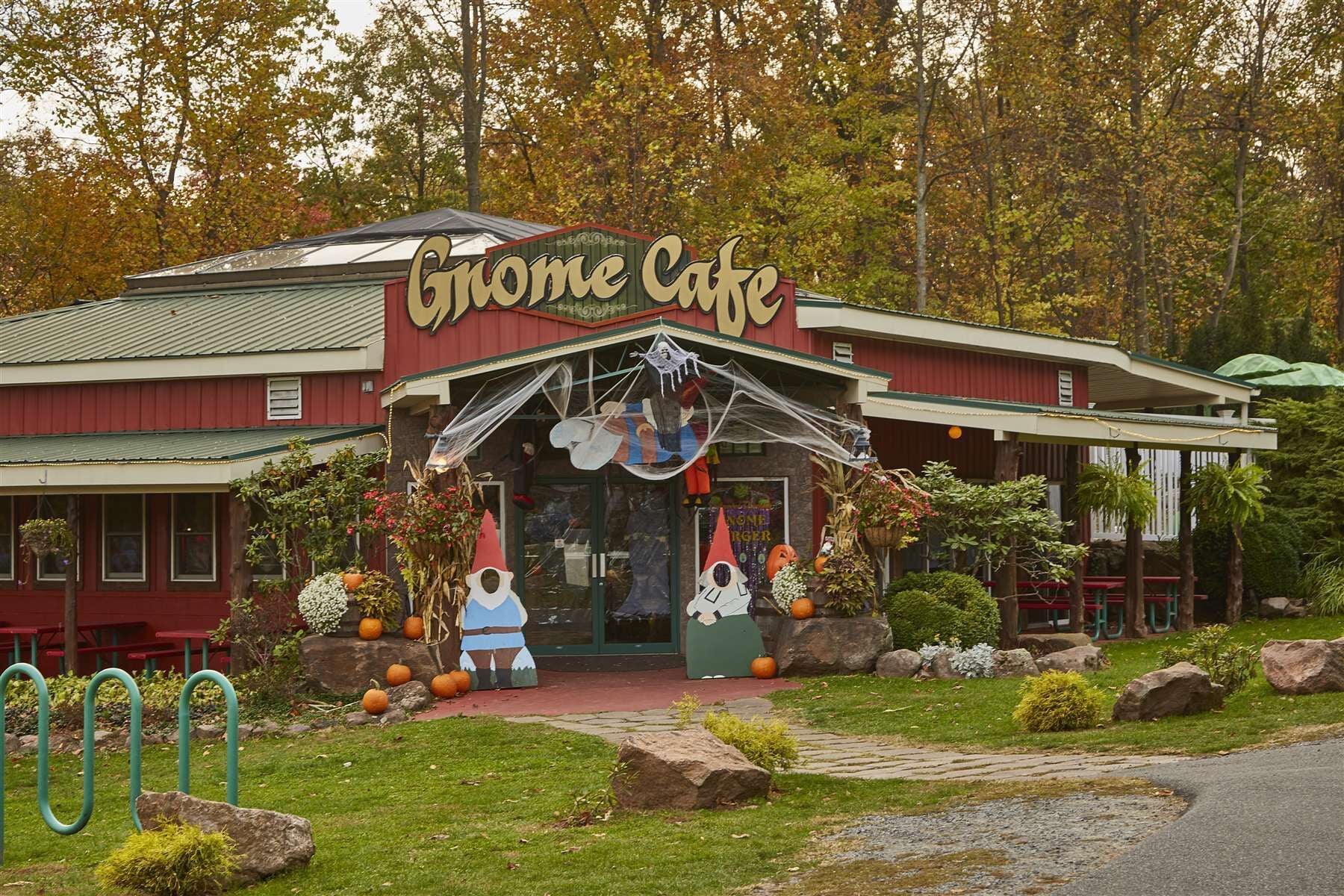 Un edificio con un letrero que dice 'Gnome Cafe' y un porche decorado con adornos de Halloween.
