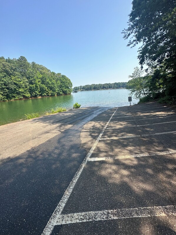 A paved area with a clear view of a lake and forested hills. - Cozy 3-bedroom, 2 full bathrooms. Enclosed Garden for pets. a large parking Lot (Anderson)