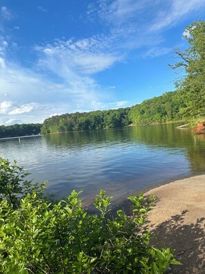 Ein See mit bewaldeter Uferlinie und blauem Himmel.