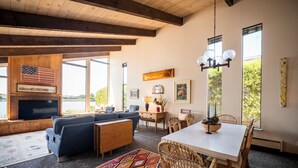 Uma sala de estar espaçosa, com uma televisão grande, assentos confortáveis e um espaço de jantar com mesa e cadeiras.