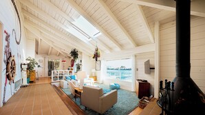 Un salón amplio con techos altos, chimenea y vista al mar.
