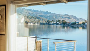 Una habitación con vista a un lago, una terraza de madera y un sillón de pelota azul.