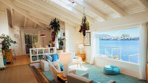 Amplia sala de estar con vistas al agua, vigas de madera en el techo y una variedad de muebles y decoración.