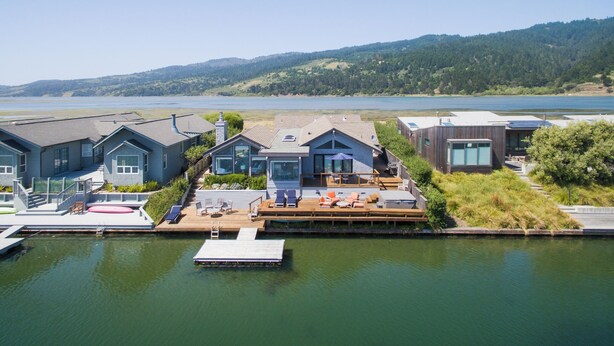 Une propriété au bord du lac comprenant plusieurs chalets, un quai et une vue sur le lac et les collines.