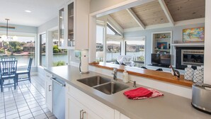 Une cuisine moderne dotée d’une grande fenêtre, d’un four encastré et offrant une vue sur l’extérieur.