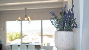A white textured pot with lavender on a windowsill in a bright room with a view.
