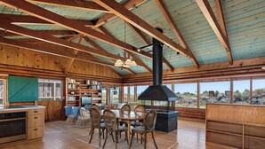 Una cabaña espaciosa con un amplio comedor, una chimenea y una biblioteca repleta de libros.