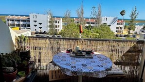 En balkon med et bord, stole og plantekasser.