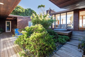 A modern house with a wooden deck, a hot tub, and a large glass window. - Impressive Oceanfront Family Home in Seadrift (Stinson Beach)