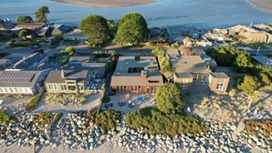 An aerial view of a coastal residential area with houses, a beach, and a rocky shoreline.