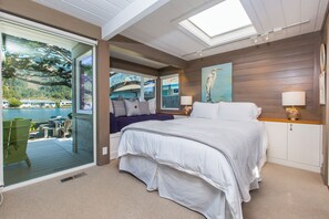 Una camera da letto con un letto grande, vista sull'esterno, un piccolo angolo salotto e un quadro appeso al muro.