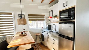 Eine moderne Küche mit Holzbalken, einem Edelstahl-Kühlschrank, einer Mikrowelle und einer Waschmaschine.
