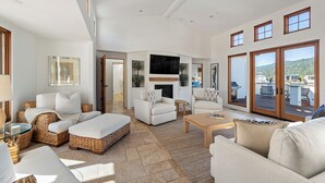 A spacious living room with a fireplace, comfortable seating, and a view of the deck. - Light and Breezy Seadrift Lagoon Home w/ Hot Tub (Stinson Beach)