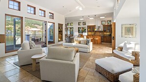 A spacious living area with a large sofa, a dining table, and a kitchen in the background. - Light and Breezy Seadrift Lagoon Home w/ Hot Tub (Stinson Beach)