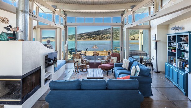 Un espacio habitable amplio con un gran ventanal que ofrece una vista panorámica del mar y las colinas.