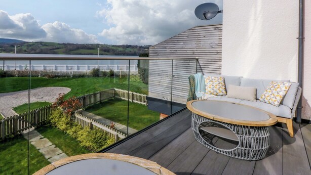 Un balcon donnant sur un lac, une table ronde et un canapé.