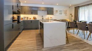 Une cuisine moderne dotée d’un îlot central, d’appareils électroménagers intégrés et d’un coin repas avec une table et des chaises.