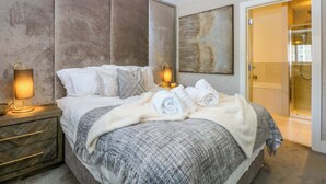 Une chambre à coucher moderne avec un grand lit, deux lampes de chevet, une tête de lit et un tableau au mur.