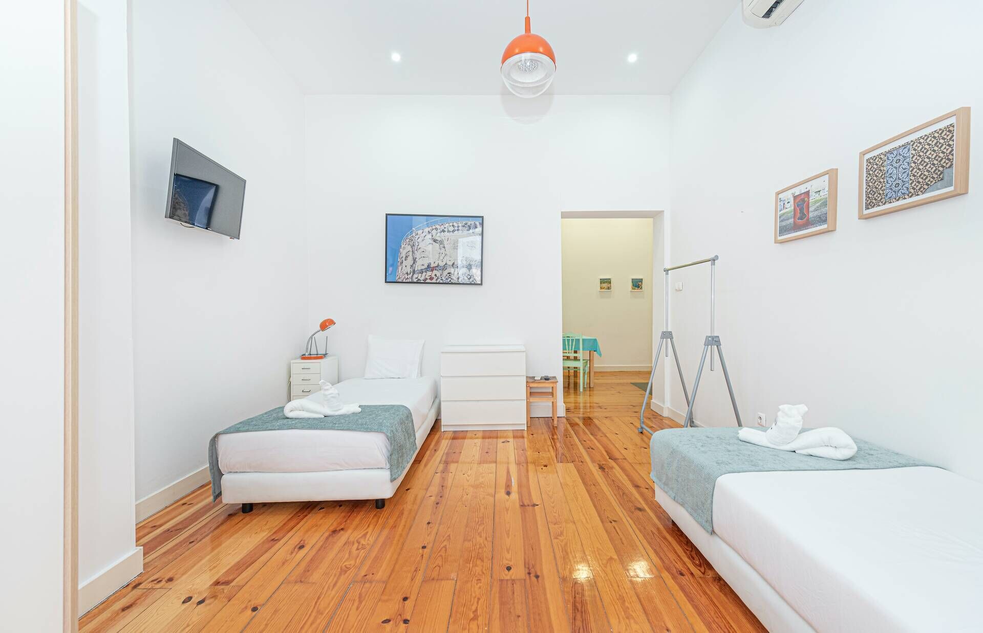 A modern hotel room with two beds, a desk, and a chair. There is a painting on the wall and a window with a view.