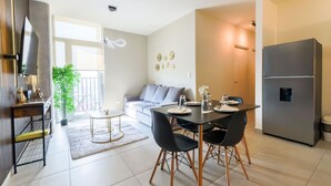 A modern living room with a sofa, dining table, chairs, and a large flat-screen TV. - ¡Cerca de Fundidora! 6 personas, GYM & Wifi 2BR1br (Monterrey)
