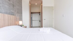 A hotel room with a large bed, a bedside table with a lamp, and a view of the hallway and kitchenette. - ¡Cerca de Fundidora! 6 personas, GYM & Wifi 2BR1br (Monterrey)