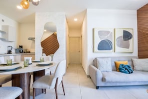 Un salon moderne comprenant un canapé, une table à manger et des chaises. Il y a également un coin cuisine équipé d’appareils électroménagers et une table à manger.