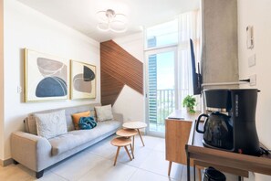 Ein stilvolles Wohnzimmer mit Sofa, Couchtisch und Essbereich mit Kaffeemaschine.