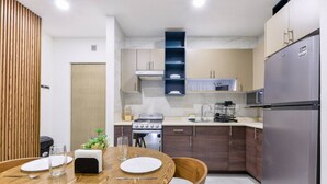 A modern kitchen with a wooden dining table, stainless steel appliances, and a built-in oven. - ¡Cerca de Fundidora! 6 ppl, GYM, Parking & 3 camas (Monterrey)