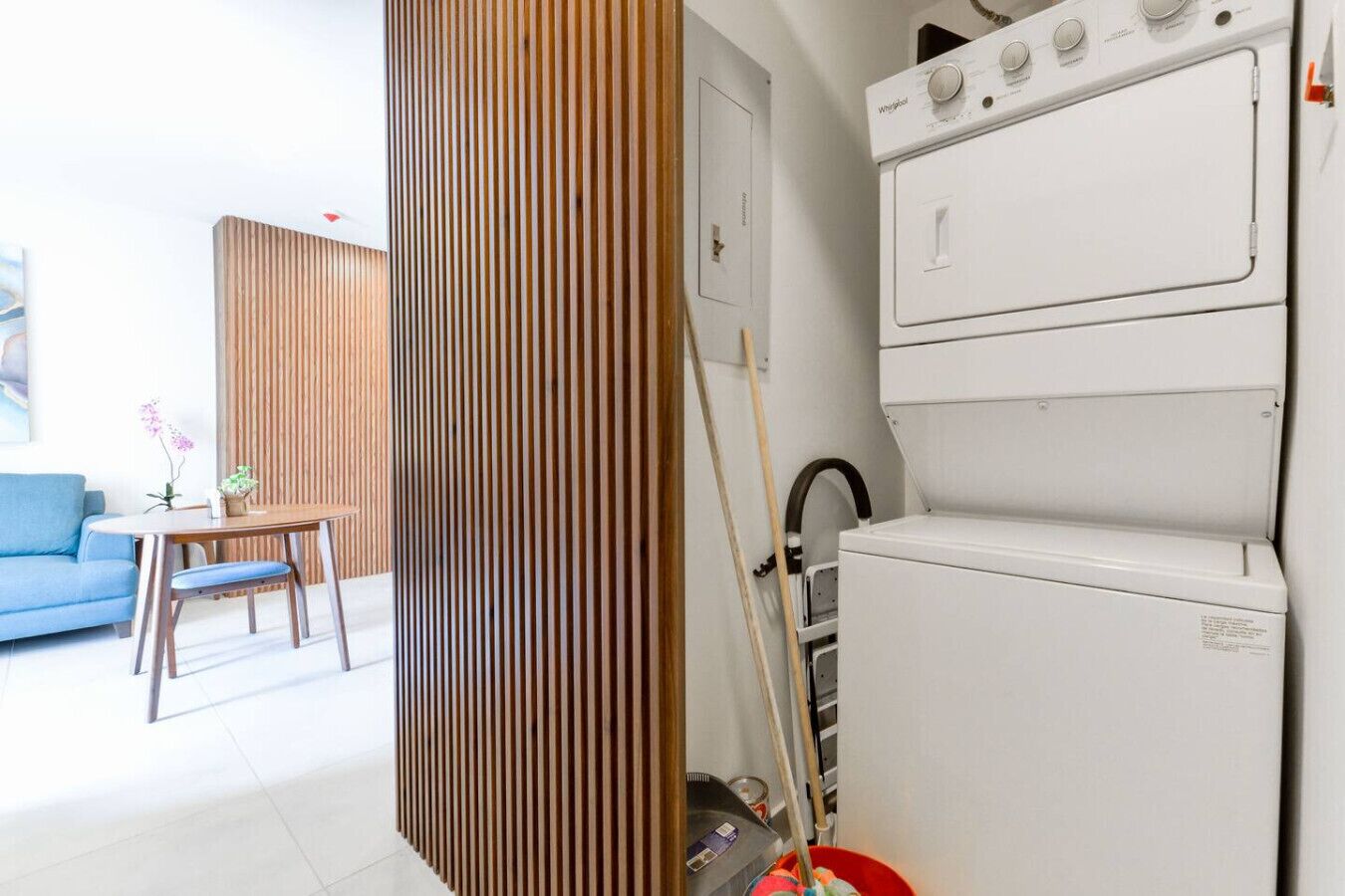 Een ruimtelijk ingerichte leefruimte met een kitchenette, een eethoek en een blauwe bank.