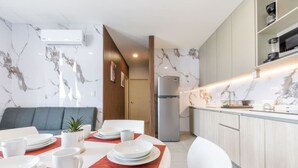 Una cocina moderna con protector contra salpicaduras de mármol, un refrigerador empotrado y un comedor con un mantel individual rojo.