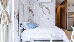 Un dormitorio con cama, mesita de noche, armario y equipo de aire acondicionado.