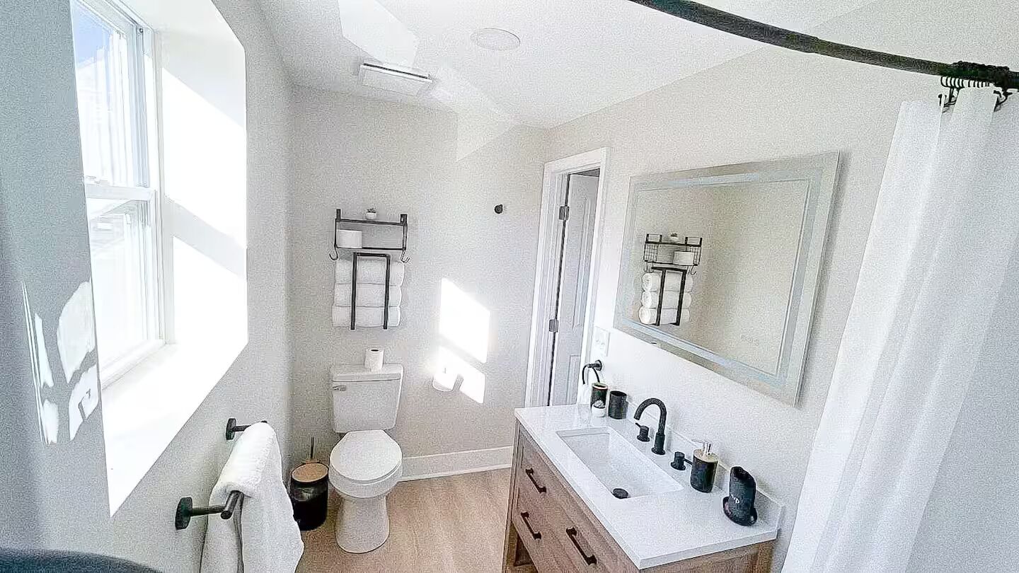 A bathroom with a toilet, sink, and mirror.