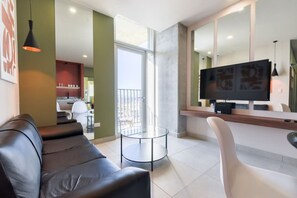 Una sala de estar moderna con un sofá de cuero, una mesa de centro de vidrio y un televisor de pantalla plana.