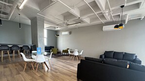 Moderni toimistotila, jossa on musta sohva, valkoiset tuolit ja ruokailutila.