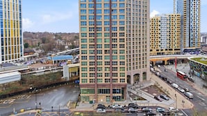 A modern high-rise building with a grid of windows, surrounded by other tall buildings and a busy street with cars and a bus. - Entire City View Apartment 8 mins to London Brigde (London)