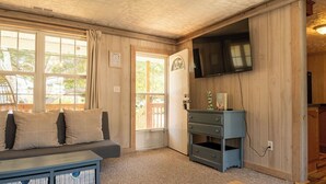 Une pièce avec un canapé, un téléviseur, un meuble en bois et une fenêtre.